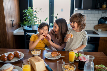 Kids eating croissants for breakfast with mom.