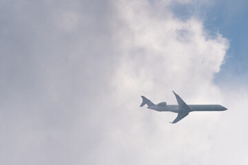 Low angle view of the airplane flying out of the white clouds
