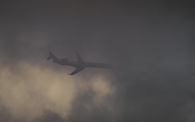 Airplane in the sky flying trough the dark cloud