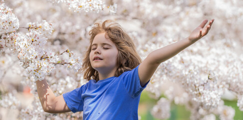 Kid in spring cherry blossom park. Peaceful kid with raised hands meditating, feeling calm near...