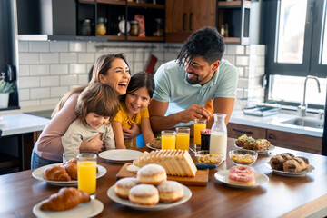 Portrait of happy family having breakfast. Parents laughing with their children at the table.