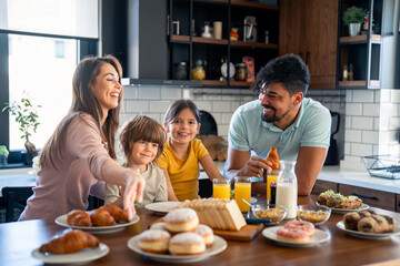 Cheerful couple with two children having breakfast at home.