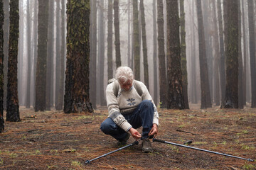 Active happy senior retired man with backpack walking in mountain forest on a foggy day stops to...