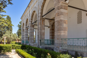View of a section of columns and arches from the garden of Karacabey Imaret Mosque. Greenery in the...