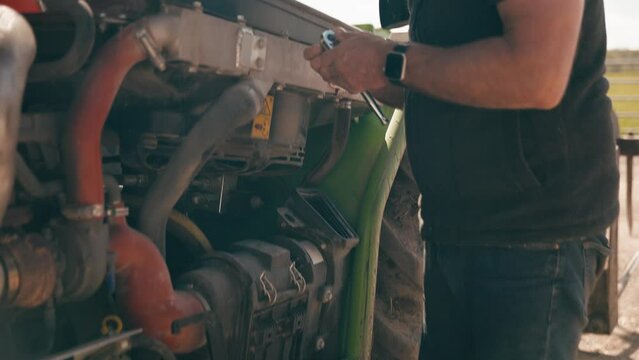 Close up of mature male farm worker with tool kit fixing machinery - shot in slow motion