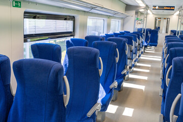 Passenger train with empty seats, with temporary blue seats. Empty interior of a long and short...