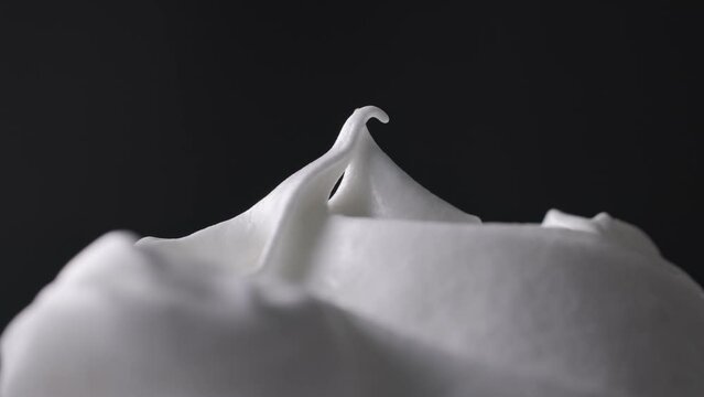 Chef mixes whipped egg whites with sugar and stirs with a spoon, dessert preparation process, close-up of food