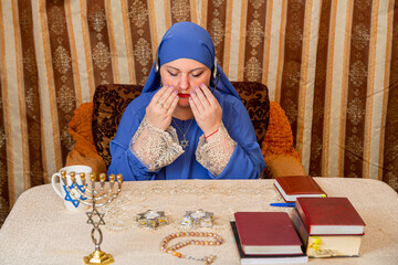 A Jewish woman at the table reads a blessing for the Shabbat candles