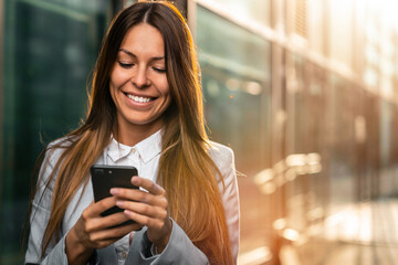 Smiling businesswoman using a mobile phone outdoors.