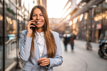 Smiling brunette female IT specialist talking on phone while standing in front of an office...