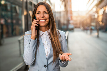 Happy businesswoman making a phone call during her morning commute in the city. Smiling...