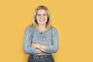 Confident middle-aged woman happy smiling on yellow background. Portrait of a confident business...