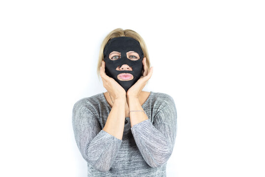 Middle-aged woman rejuvenating her facial skin with a charcoal mask, her skin is rested and looking fresh and renewed, the woman is happy and smiling