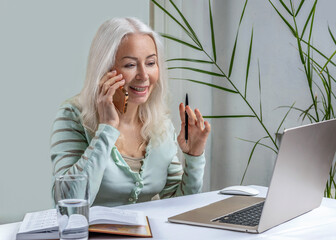Retired woman 60 years old working online sitting at home at the laptop.
