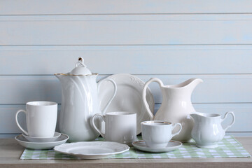 a set of white clean dishes, kitchen background. porcelain and ceramic empty dishes: cups, plates, jugs. copy space.