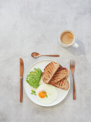 Plate with toast, egg and avocado for breakfast or brunch served with a cup of coffee. Healthy eating.