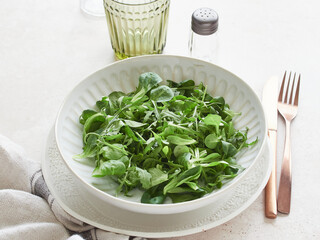 Healthy food, close up view of salad greens served on a plate. Arugula and lamb's lettuce.