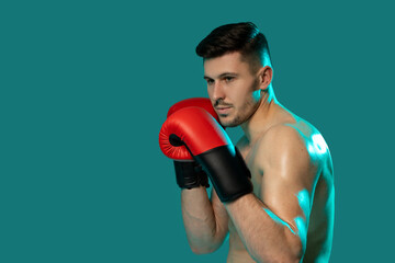 A man wearing boxing gloves strikes a pose against a vivid green background, showcasing his...