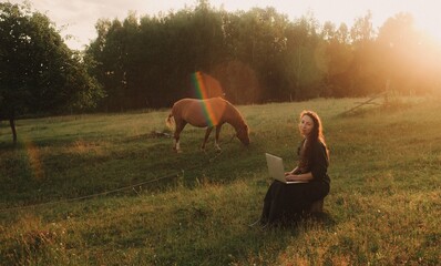 Woman using laptop in IT outside in eco-farm. Online chat. Spend free time on nature. Concept...