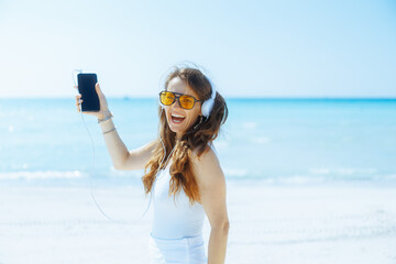 happy female on seacoast dancing and listening to music