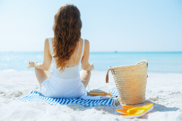 Seen from behind woman on seashore listening to music