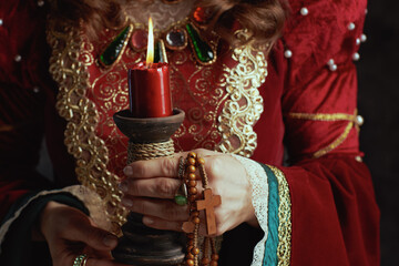 Closeup on medieval queen in red dress with candle