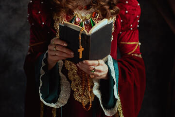 Closeup on medieval queen in red dress with book and rosary