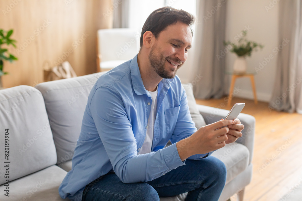 Aufkleber a man is seated on a couch, fixated on his phone screen. he appears absorbed in the digital content 