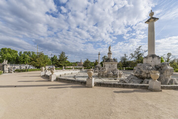 Sand promenade flanked by hedges with monumental stone fountains with monoliths and statues in the Royal Site of Aranjuez