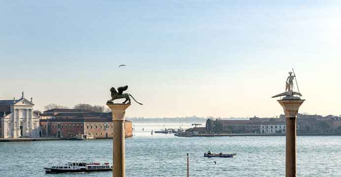 Venice, Italy - Jan 23rd, 2024: Columns of San Marco (Winged Lion) and San Teodoro with boats in the Venetian lagoon