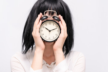 A businesswoman holding an alarm clock and covering her face