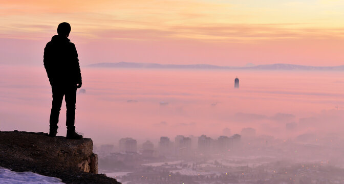 Thoughtful adventurer looking at an epic panoramic scenery during a dramatic twilight.