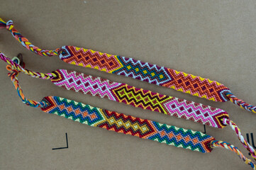 Handmade homemade colorful natural woven bracelets of friendship on brown cardboard background,...