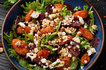 Warm baked carrots and beetroot salad with feta cheese and roasted hazelnuts