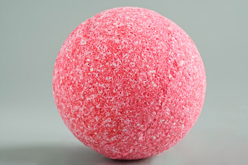 Large pink sea salt bath bomb on a light green pastel background. Porous surface of the sphere....