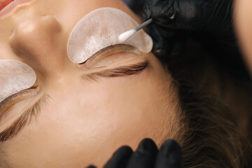 Close-up of eyelash care treatment procedures. Beautiful female, blond hair model have eyelashes...