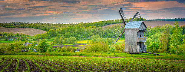 panoramic farm landscape with traditional wooden windmill in Ukraine in evening light
