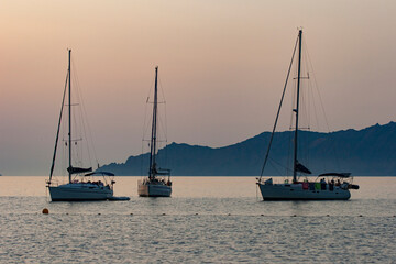 Sailing boat on bleu sunset background. Sailing boat on the sea. A sailboat at anchor in the Gulf of Porto in Corsica.