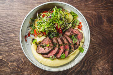 Sliced beef with herbs, served alongside puree and a side salad.