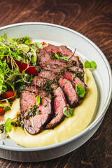 Sliced beef with herbs, served alongside puree and a side salad.
