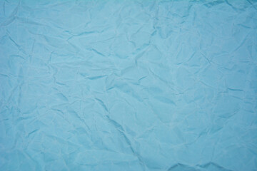 Light blue background with dense wrinkles. Light blue color recycled kraft paper texture as...