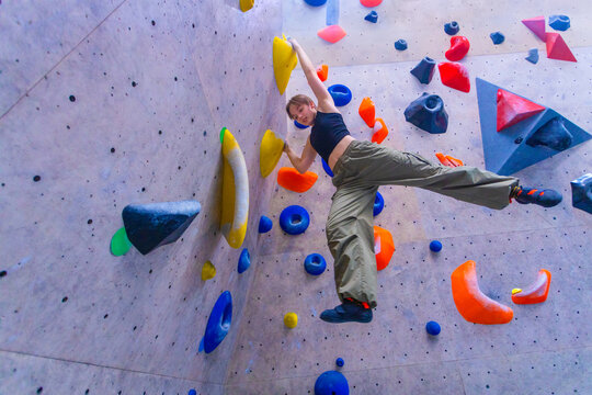 Bouldering climbing athlete woman training at indoor gym boulder climb wall. Teenager fit girl going up having fun in extreme sport hobby. Social media template - Powered by Adobe
