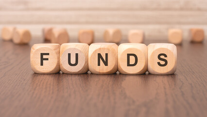 the text 'FUNDS' is written on wooden cubes on a brown background