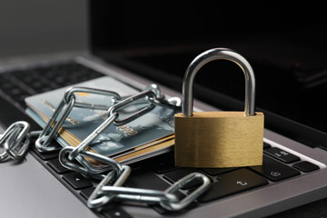 Cyber security. Metal padlock, chain and credit cards on laptop, closeup