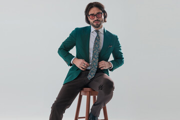 cool fashion businessman with sunglasses buttoning green suit