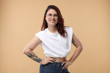 Portrait of beautiful tattooed woman on beige background