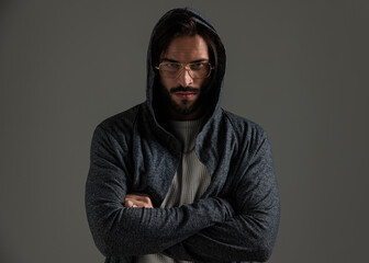 portrait of tough casual guy with hoodie and glasses crossing arms