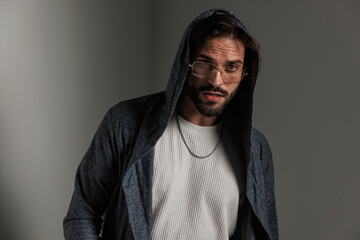 sensual young man with hoodie and glasses looking forward and posing