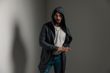 sexy casual man with long hoodie rubbing palms and posing