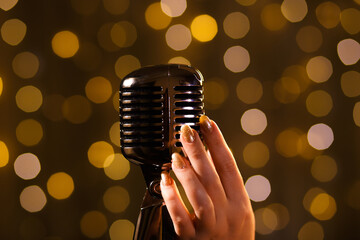 Female hand with retro microphone, close-up. Woman singing songs on the stage